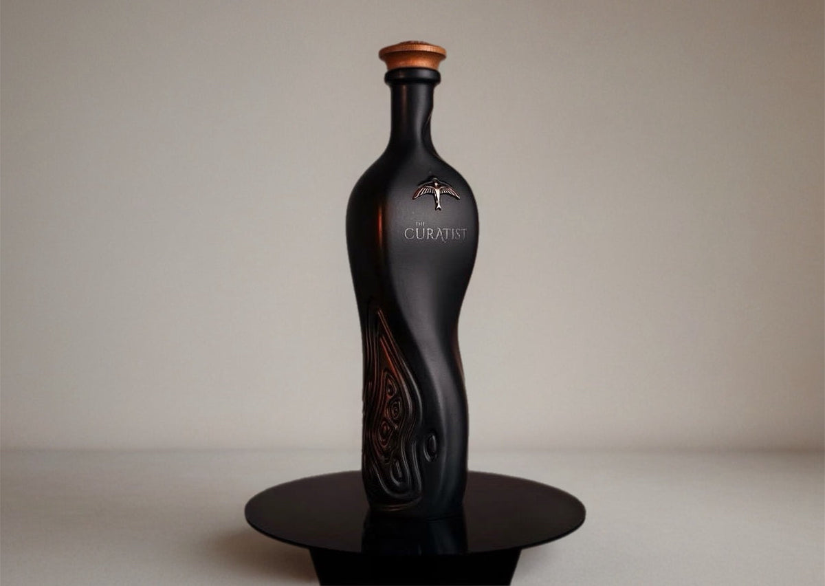 The Curatist luxury drink bottle displayed elegantly on a black stand.